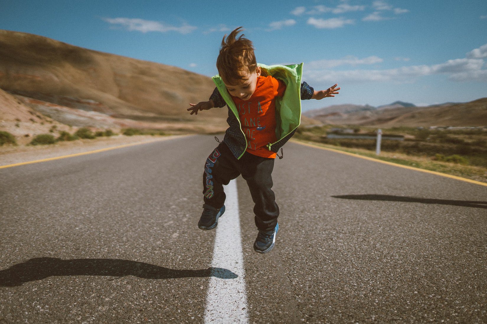 child jumping on road