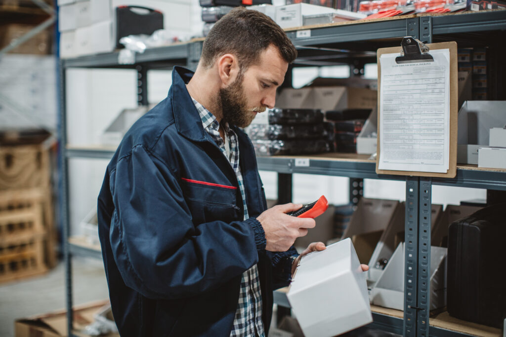 Distribution worker working in warehouse. He is collecting information about stock manually.