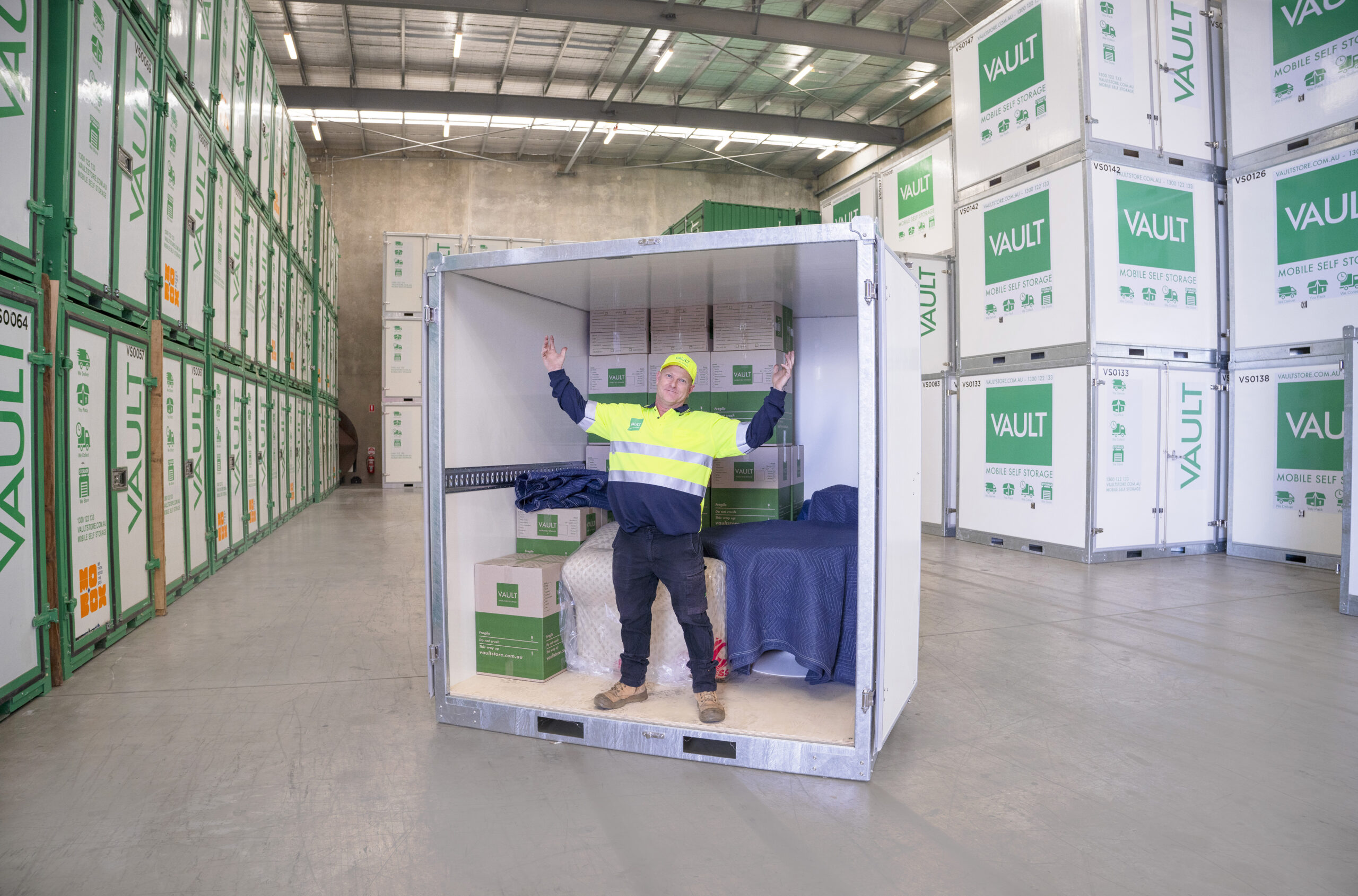 Worker standing beside a secured storage container inside the facility, showcasing organised Art Studio Storage solutions.